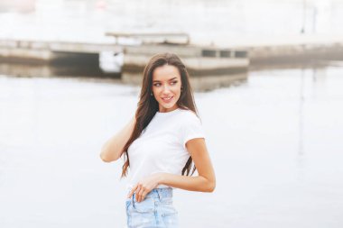 Genç, güzel, mutlu bir kadın marinada sahilde yürüyor. Pozitif, seyahat, özgürlük. Avrupa