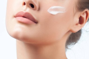 Genç ve güzel bir kadın kusursuz cildine krem sürüyor. Güzellik portresi.