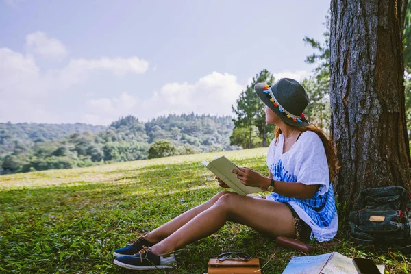 Mujer asiática viaje naturaleza. Relájate. Chica sentada leyendo un libro bajo el árbol. Hermosa chica en el bosque de otoño leyendo un libro Nature Education y escribir una nota . — Foto de Stock