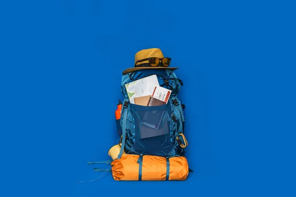 Tourist planning vacation with the help of world map with other travel accessories around. concept Luggage with accessory for travelers Vacation on Blue color background. Travel backpack