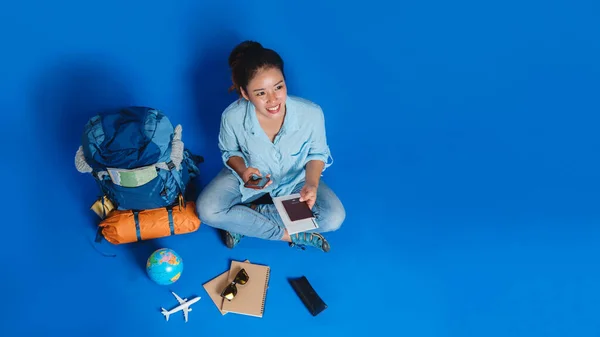 Touristische Planung Urlaub mit Hilfe von Weltkarte mit anderen Reise-Accessoires herum. Frau Reisende mit Koffer auf blauem Hintergrund. — Stockfoto