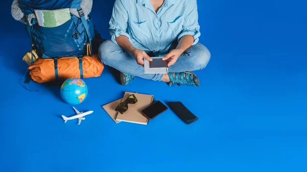 Touristische Planung Urlaub mit Hilfe von Weltkarte mit anderen Reise-Accessoires herum. Frau Reisende mit Koffer auf blauem Hintergrund. — Stockfoto
