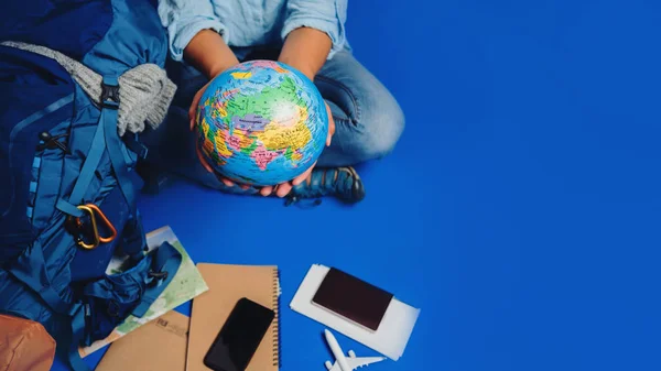 Touristische Planung Urlaub mit Hilfe von Weltkarte mit anderen Reise-Accessoires herum. Frau Reisende mit Koffer auf blauem Hintergrund — Stockfoto