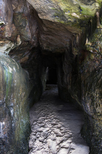 Туннель со стороны океана через скалу с песчаным дном, ведущим в пещеру
