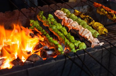 Street food/Traditional Grilled tandoori of  assorted meats with charcoal and fire on skewers clipart
