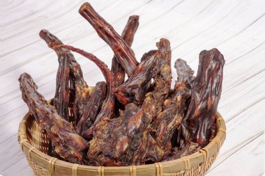 Kurutulmuş öküz kuyruğu dolu saman kasesi. Egzotik yemeklerde ya da büyük köpekler için doğal çiğneme tatlısı olarak kullanılabilir. Susuz yiyecekler. Kapalı alan, beyaz arkaplan, kopyalama alanı.