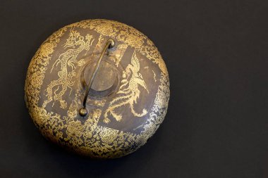 Yüzeyinde altın eşyalar, ejderhalar ve çiçek temalı eski Çin yapımı koyu metal tencere. Asya tarihi eseri. Siyah arkaplan, stüdyo, kopyalama alanı.
