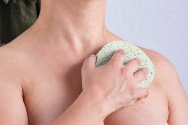 Duşta vücudunu süngerle temizleyen bir kadın.