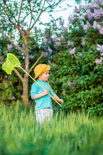 Seorang anak yang menawan bermain dengan sendok di padang rumput di musim panas yang hangat dan cerah atau musim semi . — Stok Foto