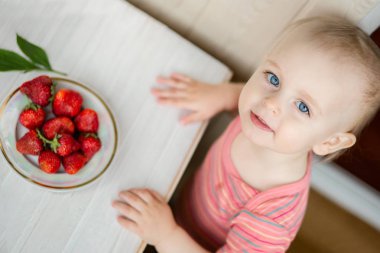 Elini bir çocuğun rustik bir arka planda bir tabak çilek Çilek ile.