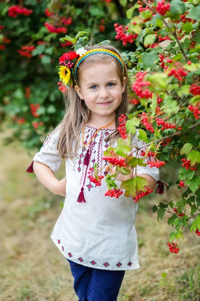 A little girl with blond hair in a Ukrainian folk costume stands near — Stock Photo, Image