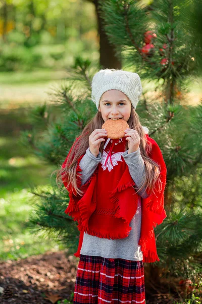 Cute girl eating Christmas cookies on a background of the New Year tree. Winter holidays and people concept. — Stock Photo, Image