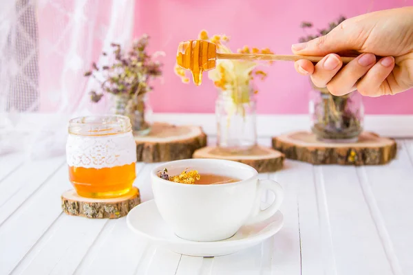 White cup of tea with linden in natural organic herbs and a jar of honey on a white wooden table. — Stock Photo, Image