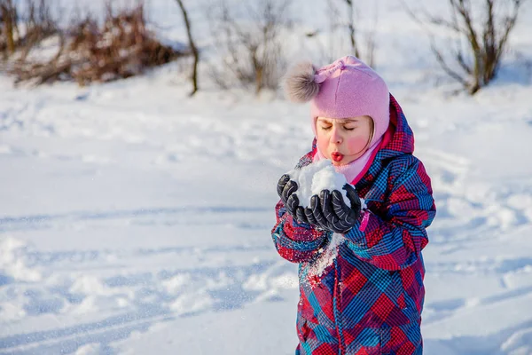 Cheerful girl throws snow on a sunny winter day. Active games with snow. The winter vacation.