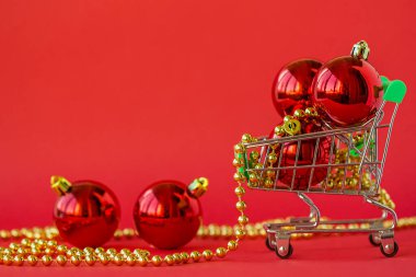 Minyatür bir tramvayda hediye topları ve kırmızı arka planda süslemeler. Noel ve Yeni Yıl Satışı.