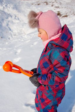 Karlı kış yürüyüşünde karla oynayan mutlu kız, parkta kartopu yapıyor..