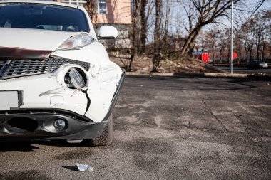 Araba kazası ya da kaza. Ön kanat ve sağ far kırılmış, tamponda hasar ve çizikler var. Kırık araba parçaları ya da yakın çekim.