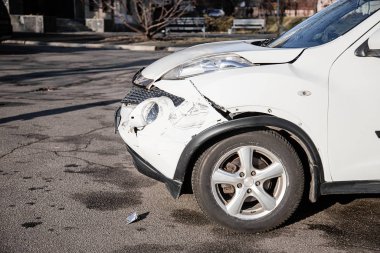 Araba kazası ya da kaza. Ön kanat ve sağ far kırılmış, tamponda hasar ve çizikler var. Kırık araba parçaları ya da yakın çekim.