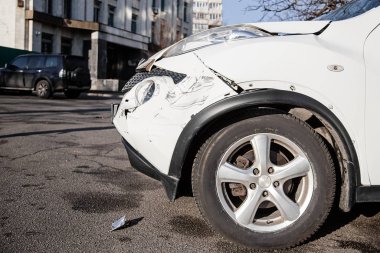 Araba kazası ya da kaza. Ön kanat ve sağ far kırılmış, tamponda hasar ve çizikler var. Kırık araba parçaları ya da yakın çekim.