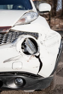 Araba kazası ya da kaza. Ön kanat ve sağ far kırılmış, tamponda hasar ve çizikler var. Kırık araba parçaları ya da yakın çekim.