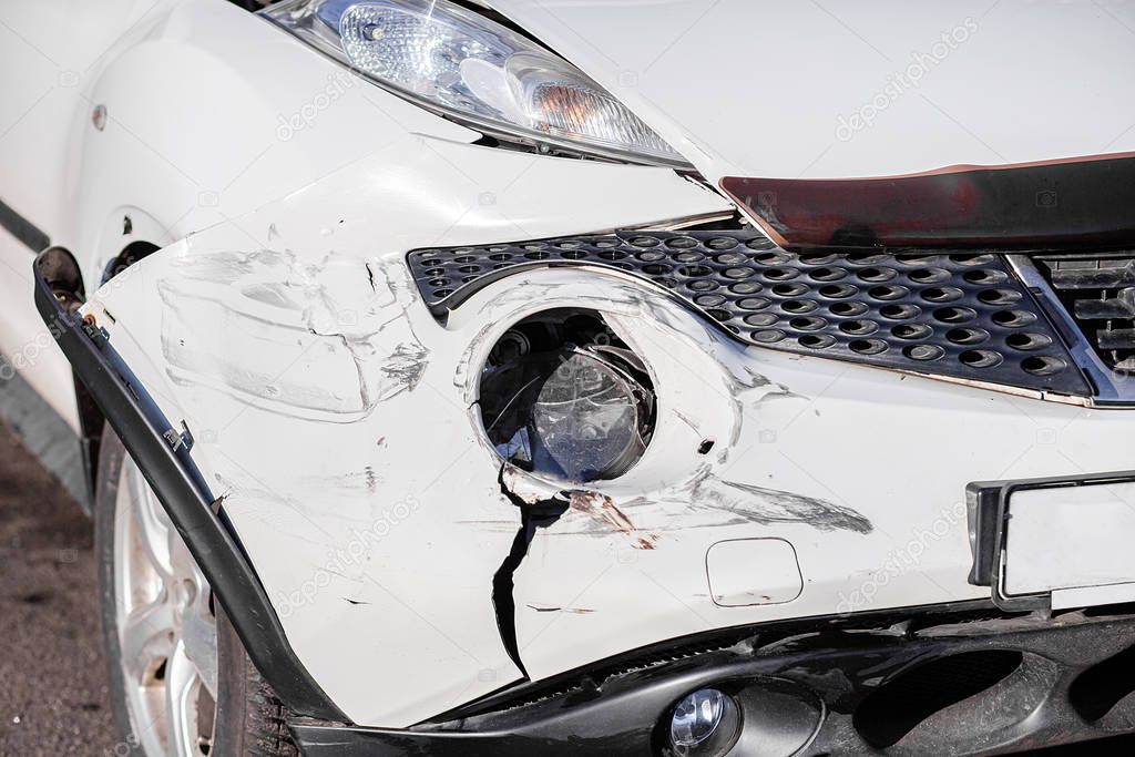 Inspection of the car after an accident on the road. The front fender and left headlight are broken, damaged and scratched on the bumper.