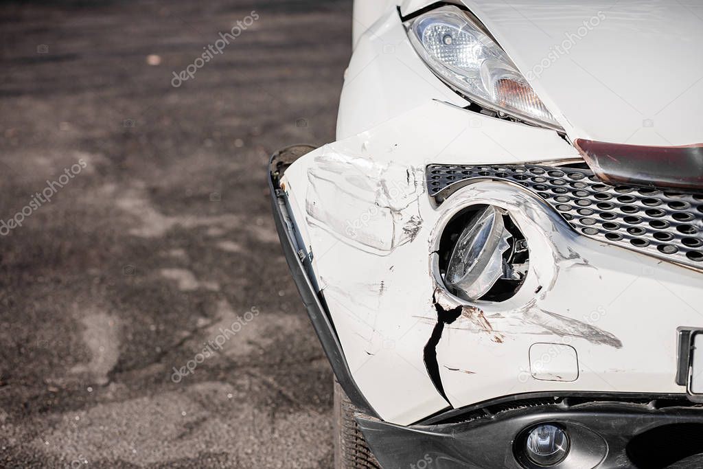 Inspection of the car after an accident on the road. The front fender and left headlight are broken, damaged and scratched on the bumper.