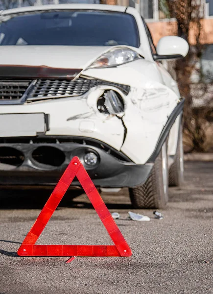 在路上关上汽车紧急停车标志. 前挡泥板和右前灯在保险杠上被打破、损坏和划伤. — 图库照片