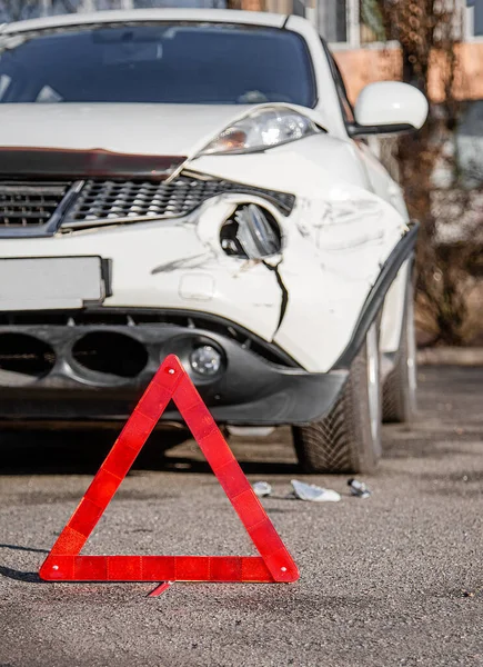 Feche o sinal de parada de emergência do carro na estrada. O pára-choques dianteiro e o farol direito estão quebrados, danificados e arranhados no pára-choques . — Fotografia de Stock