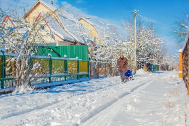 Babam çocukları kızakla gezdirir. Soğuk bir kış gününde ailemle birlikte yürüyorum..