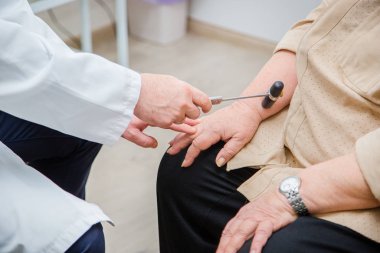 Diz refleksini kontrol eden ortopedik cerrah. Doktor, fizyolojik refleksi ve test çekicini kontrol ediyor..