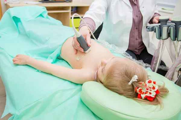 Kadın doktor ultrason tarayıcısıyla kalp bölgesini inceliyor..