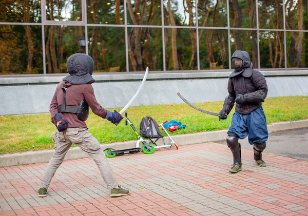 Dos hombres armados lideran una lucha con espadas, una lucha medieval, en un divertido torneo medieval. Competiciones deportivas . —  Fotos de Stock