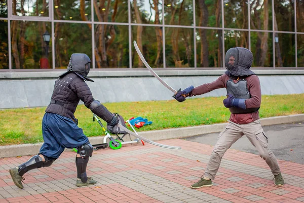 Two armed men lead a sword fight, a medieval fight, at a fun medieval tournament.