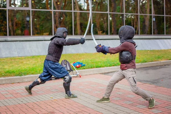 Two armed men lead a sword fight, a medieval fight, at a fun medieval tournament. Sports competitions.