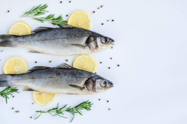 Beyaz bir masa üzerinde baharat ve bitkilerle çiğ deniz levreği. Taze deniz levreği.