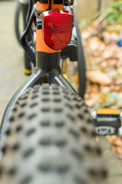 Bicycle tire rear wheel with studs and reflective tail light in red — Stock Photo, Image