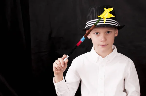Chłopiec w białej koszuli, kapeluszu i magicznej różdżce patrzy prosto w kamerę — Zdjęcie stockowe
