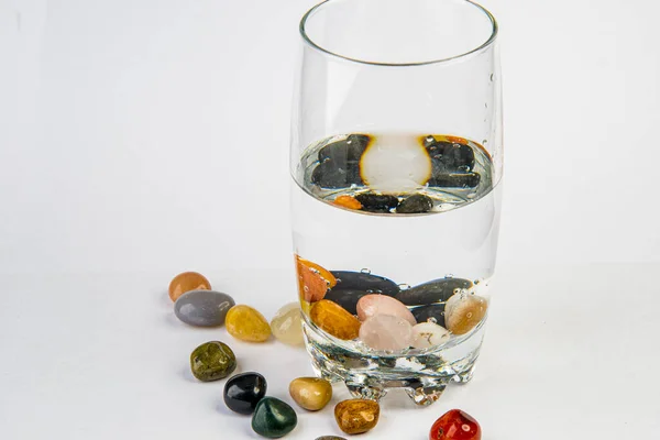 Стекло с водой и целебные камни для альтернативного напитка — стоковое фото