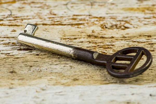 Alter gebogener Schlüssel zu einer Schatztruhe auf altem Holz — Stockfoto
