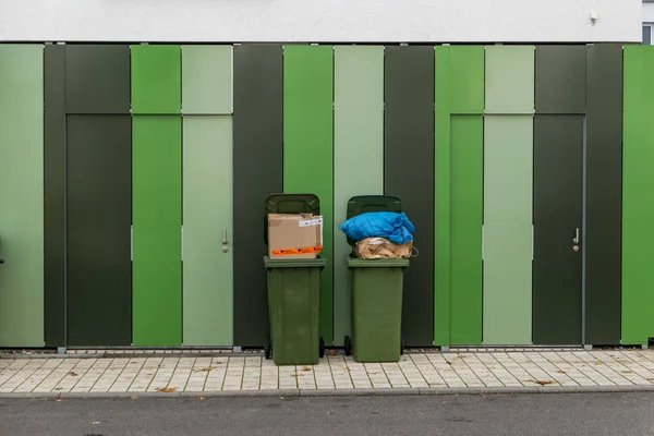 Twee overgevulde vuilnisbakken op een gestreepte muur — Stockfoto