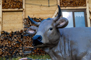 Odun yığınının önünde plastik bir inek.