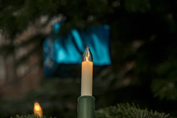 Одинокая рождественская свеча перед елкой с голубым подарком — стоковое фото