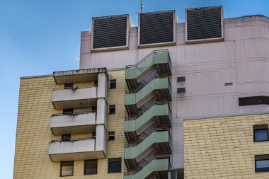 Seksenlerin tarzında harici merdivenleri olan yüksek katlı bir bina.