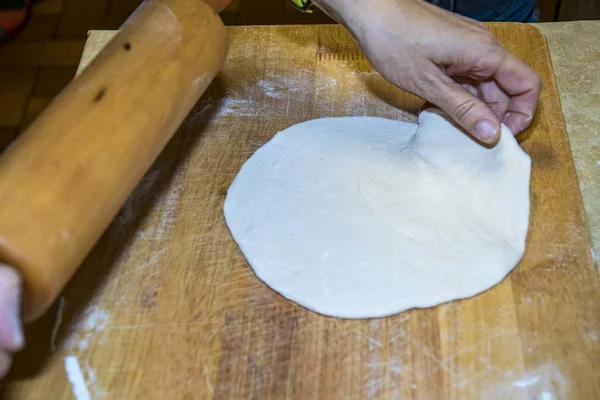 La masa de pizza redonda se despliega con harina y tablero de madera —  Fotos de Stock