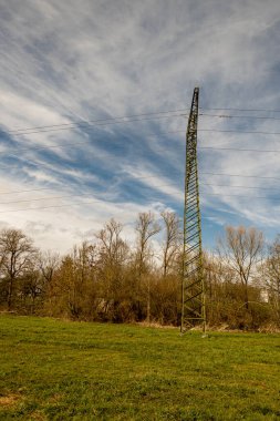Bulutlu bir gökyüzünün önünde doğadaki elektrik direkleri