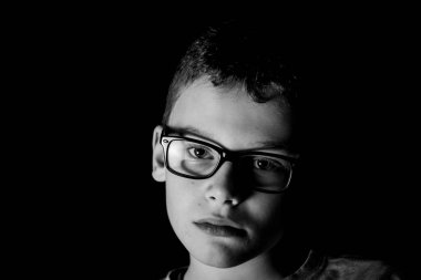 Evde uzun süre kaldıktan sonra okullu çocuk kameraya gergin bakıyor.