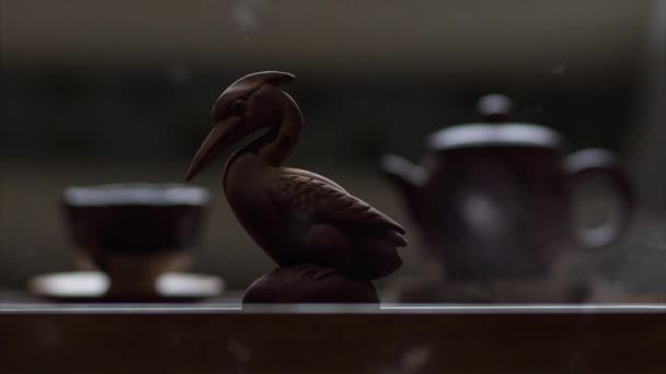 Närbild Heron Figurine Och Suddig Kopp Och Tekanna Bakgrunden Aska — Stockvideo