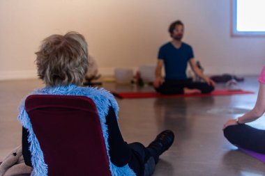 Yoga sınıfında oturan bir kadın.