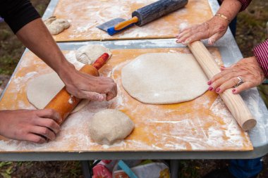 İnsanlar pizza donutlarını yoğuruyor. Açık hava ekmek atölyesinin bir parçası olarak.