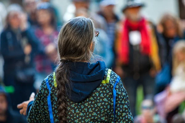 Mujer con el pelo platinado y gafas está dando un discurso público — Foto de Stock